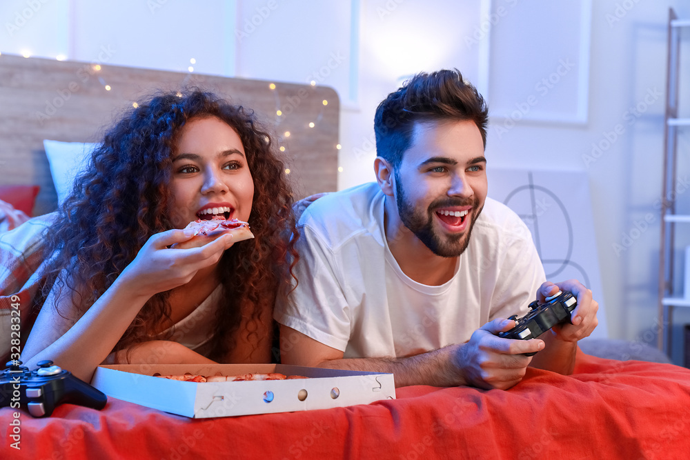 快乐的年轻情侣在卧室玩电子游戏