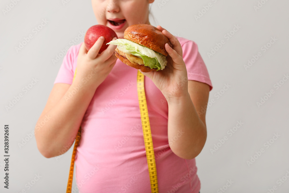 超重女孩在浅色背景下吃健康和不健康的食物