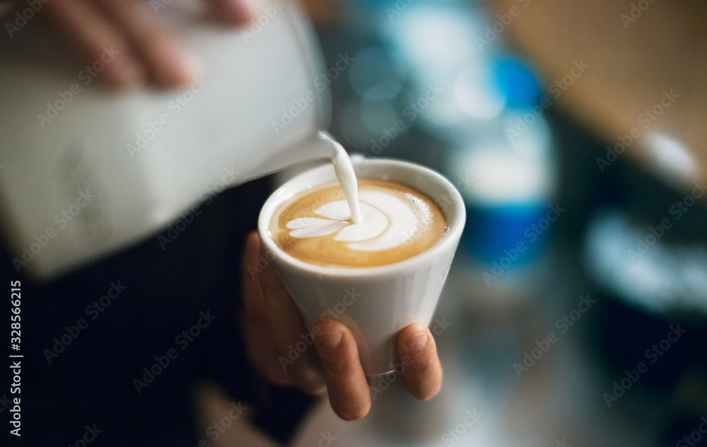 专业咖啡师将拿铁泡沫倒在咖啡、意式浓缩咖啡上，打造完美的卡布奇诺