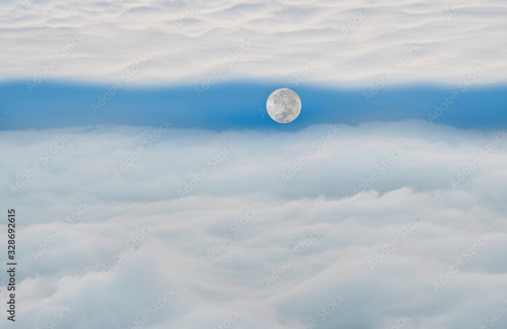 月亮漂浮在两个云平面之间，早上有蓬松的云和蓝天