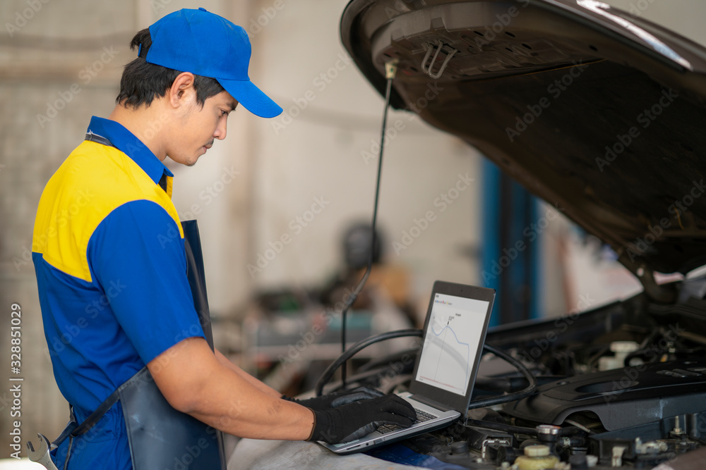 Car repair technicians use laptop computers to measure engine values for analysis