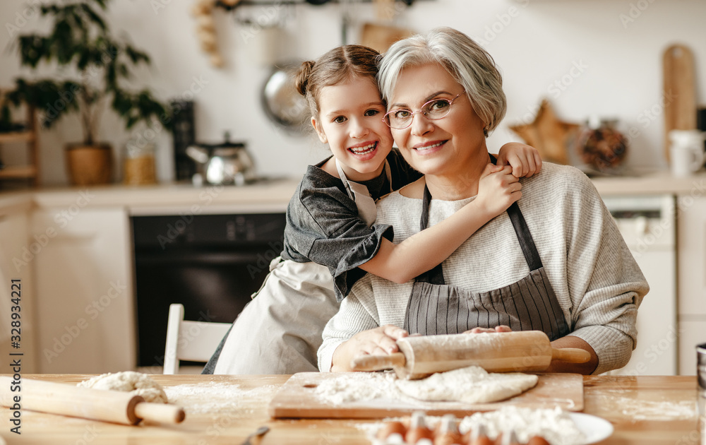 幸福家庭的祖母和孙女在厨房做饭，揉面团，烤饼干。