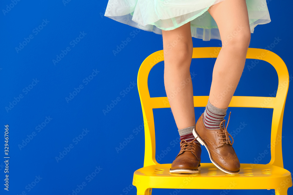 小女孩站在彩色背景的椅子上