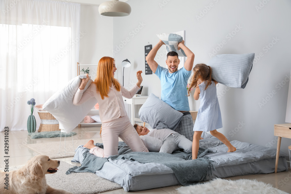 幸福的一家人在家里卧室枕头上打架