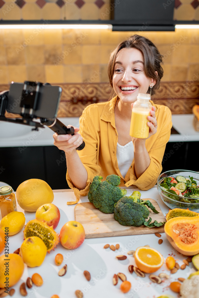 Young and cheerful woman vlogging on mobile phone about healthy food and cooking. Concept of healthy