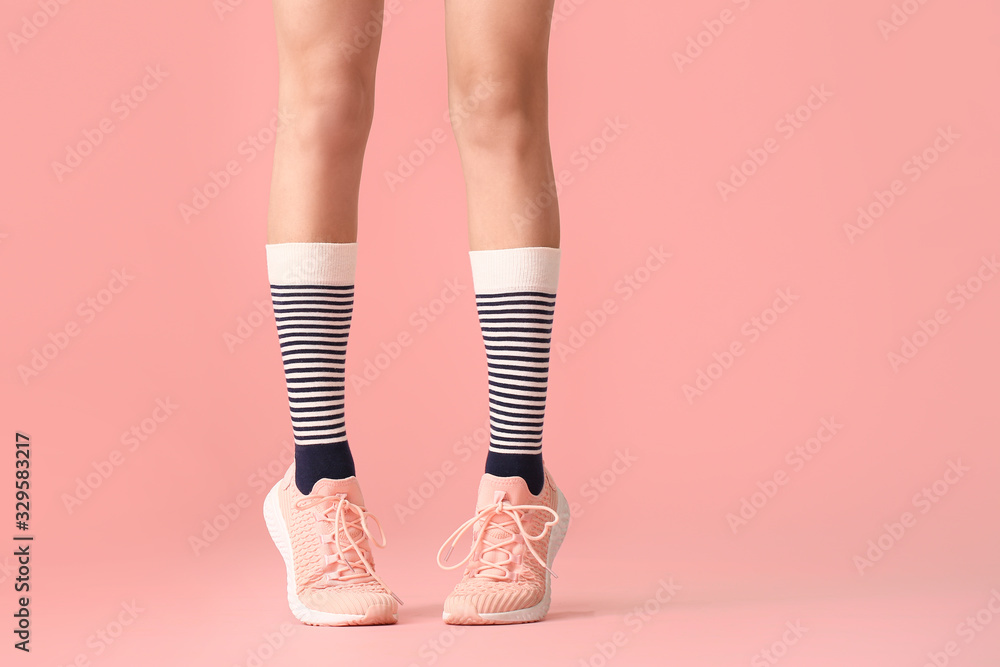 彩色背景下穿着袜子和鞋子的年轻女子的腿