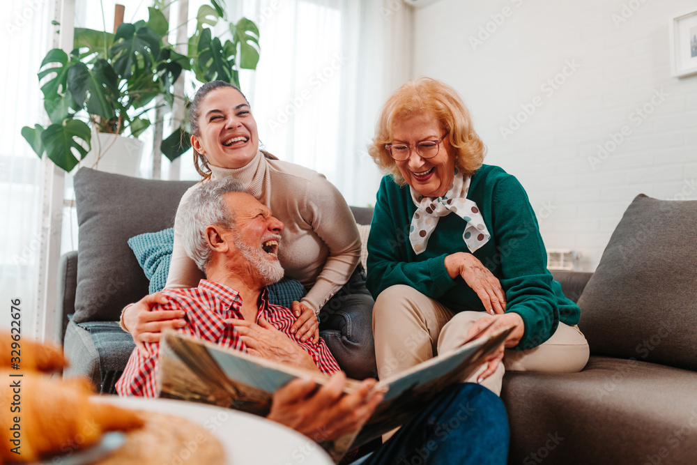 快乐的一家人坐在客厅里看着家庭相册里的旧照片时开怀大笑