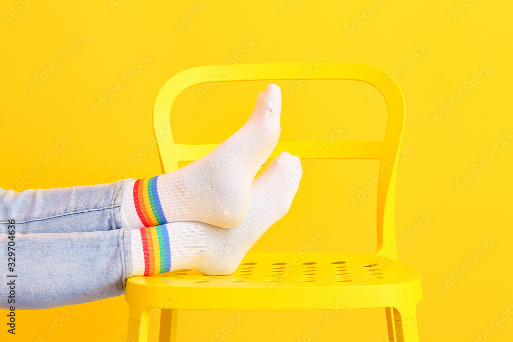 彩色背景下椅子上穿着袜子的年轻女子的腿