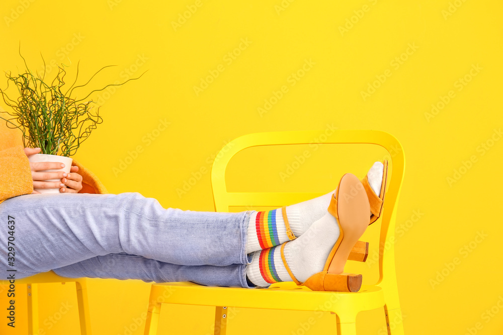 背景色椅子上穿着袜子和凉鞋的年轻女子的腿