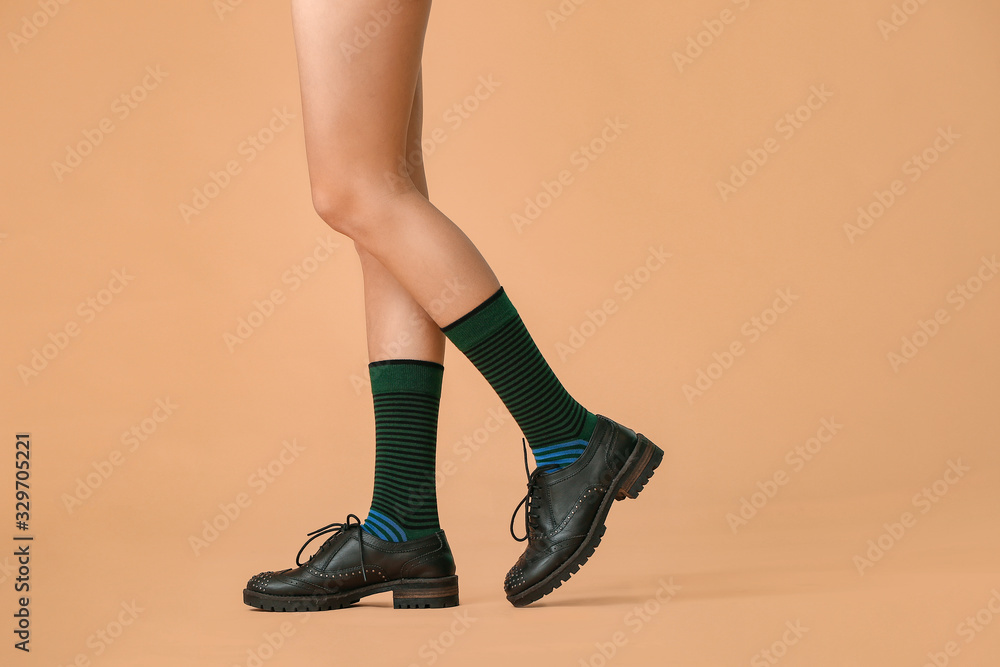 彩色背景下穿着袜子和鞋子的年轻女子的腿