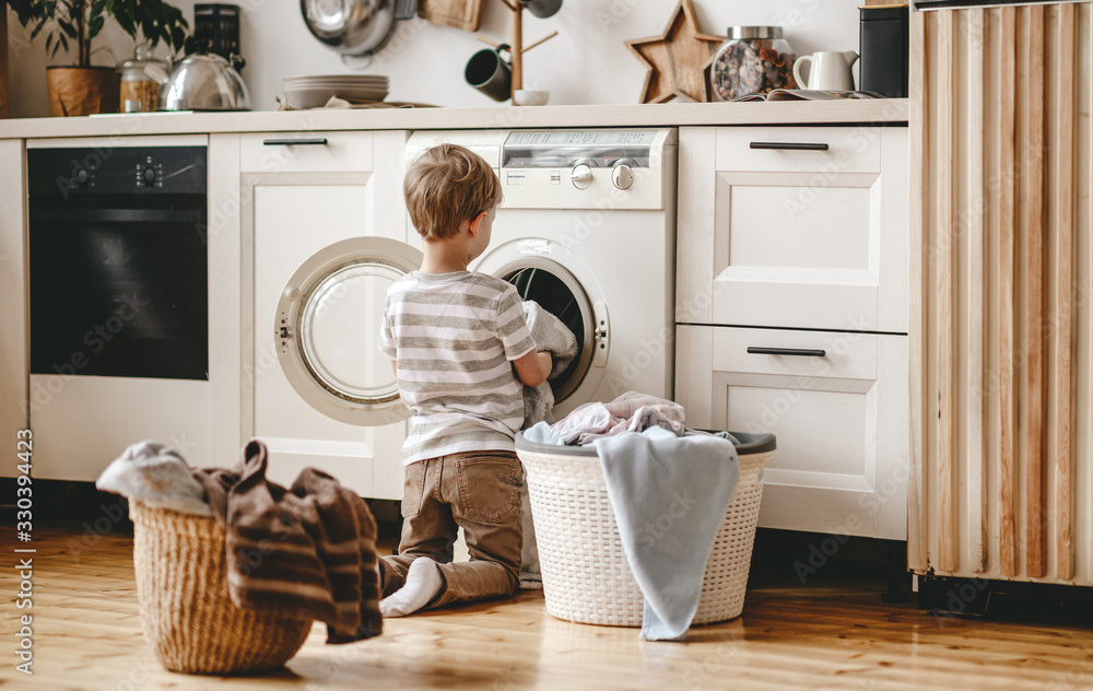 Anonymous   householder child boy in laundry   with washing machine