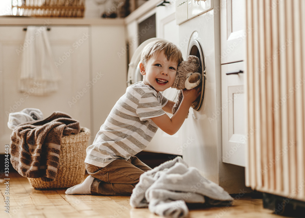 快乐的户主小男孩在洗衣房里用洗衣机