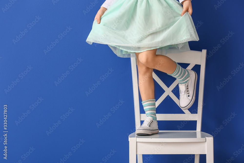 小女孩站在彩色背景下的椅子上