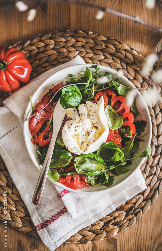Flat-lay of traditional Italian salad with Buratta cheese, tomatoes, arugula and fresh basil in whit