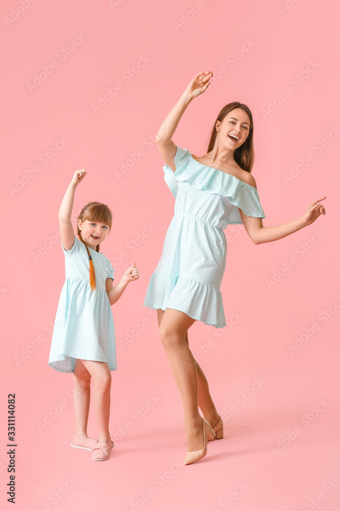 快乐的母亲和她的小女儿在彩色背景下跳舞