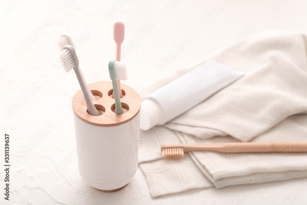Tooth brushes, paste and towel on light background
