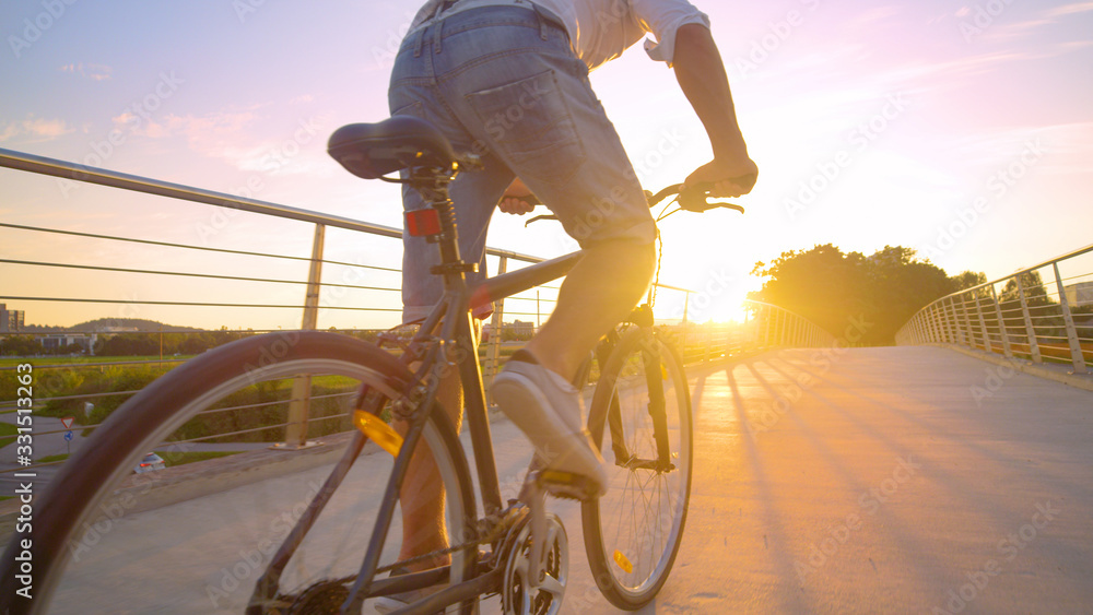 LENS FLARE：一名无法辨认的男子匆忙骑着自行车穿过立交桥。