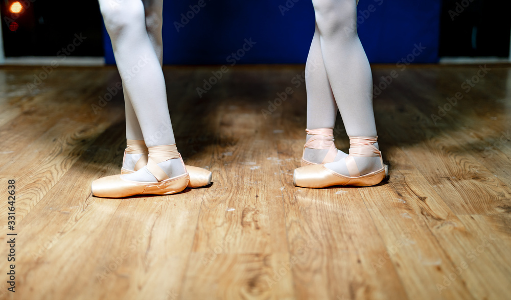 年轻芭蕾舞演员的腿。在芭蕾舞课上排练。穿着白色连裤袜和芭蕾舞鞋。