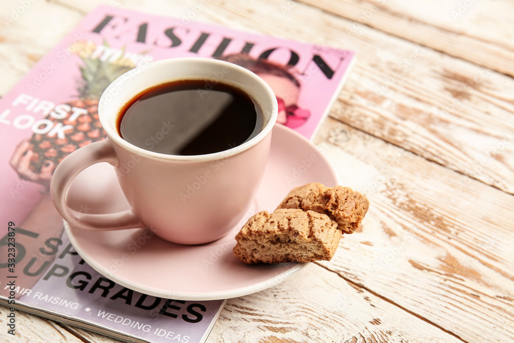 Cup of hot coffee, cookies and fashion magazine on wooden background