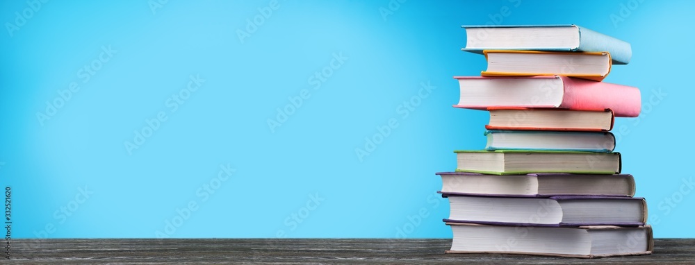 Stack of colorful school books on wooden desk