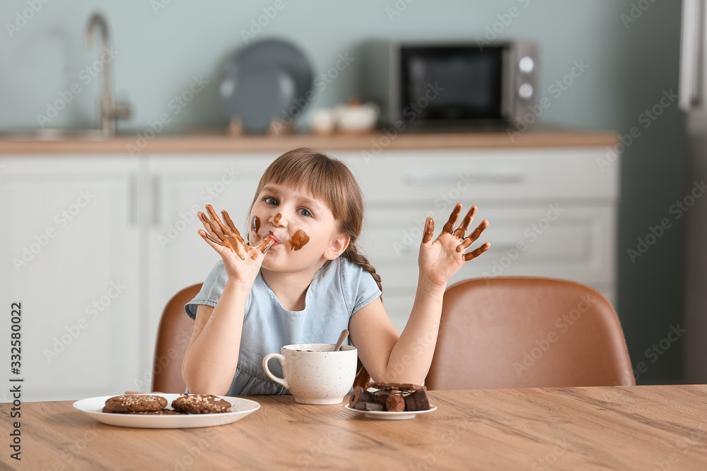 可爱的小女孩在厨房吃巧克力