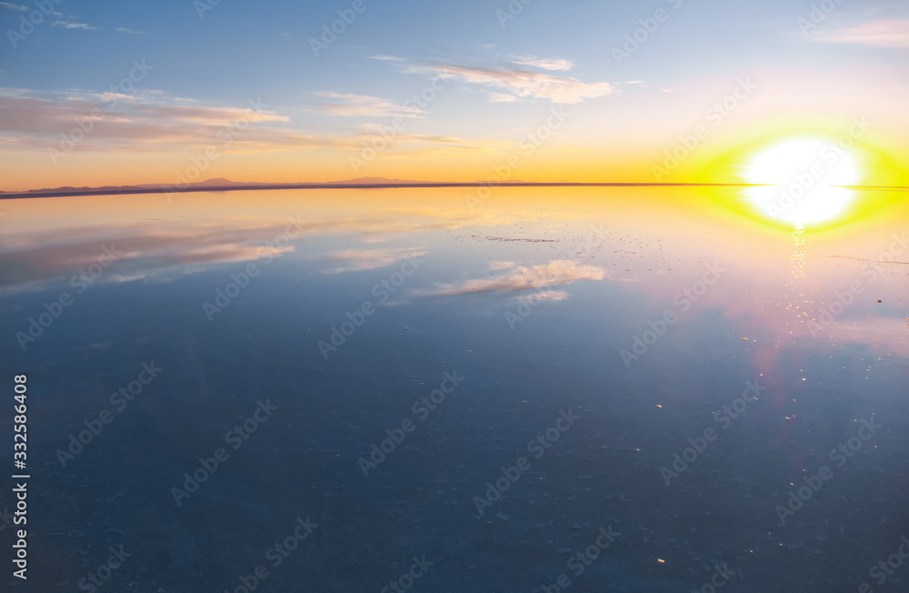 玻利维亚乌尤尼盐湖的日出被水、盐碱地沙漠和天空反射所覆盖