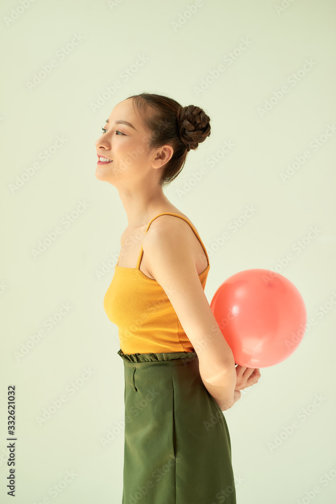 快乐快乐的亚洲女孩在灯光背景下拿着粉红色的气球。