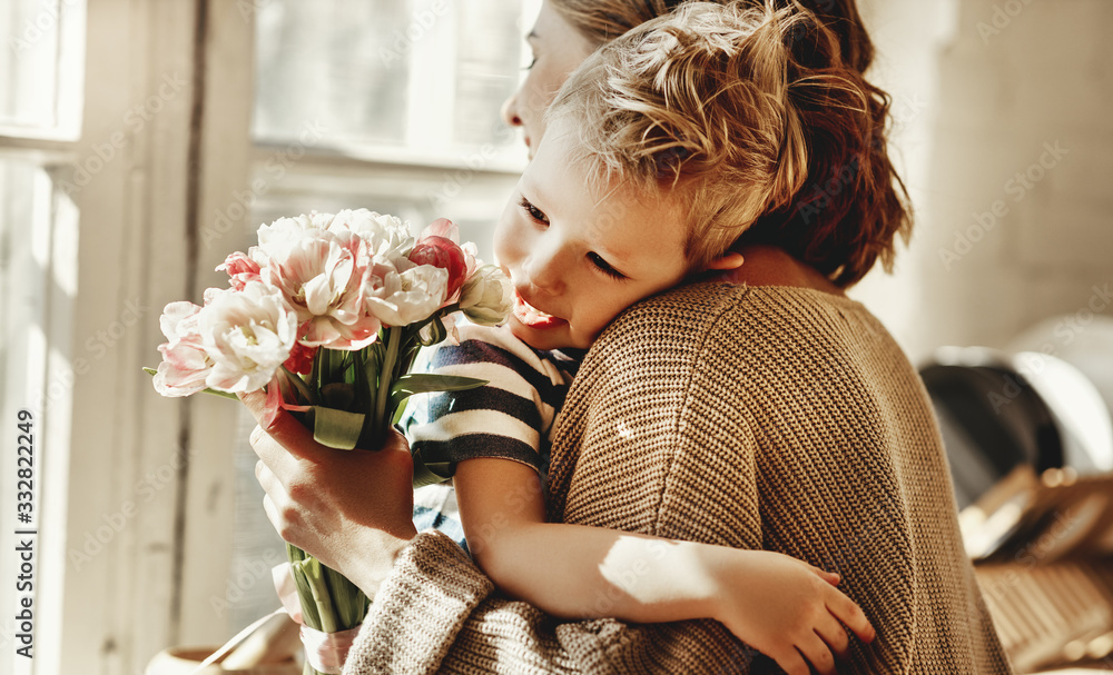 Happy mother with flowers hugging little son.