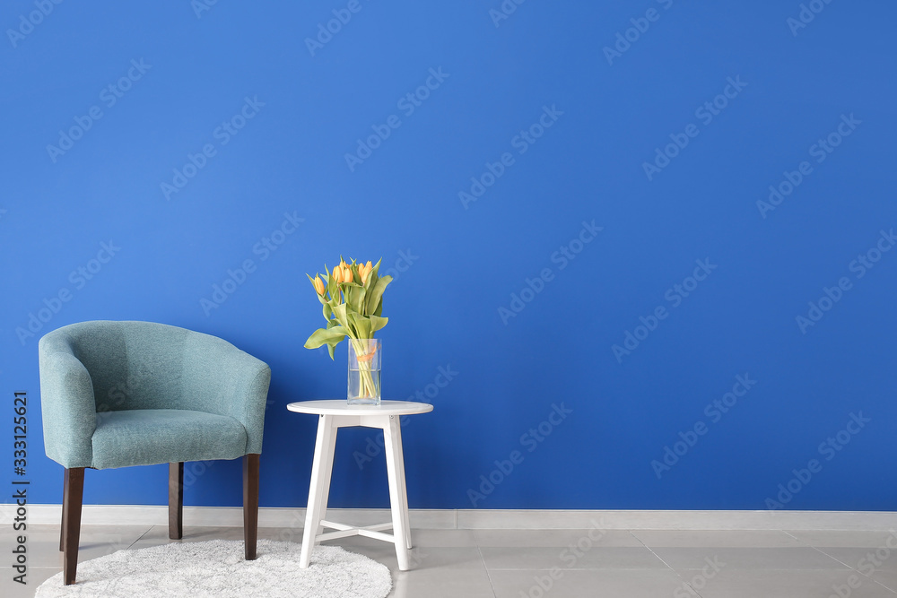 现代房间内部，配有舒适的扶手椅和靠近彩色墙的春花桌子