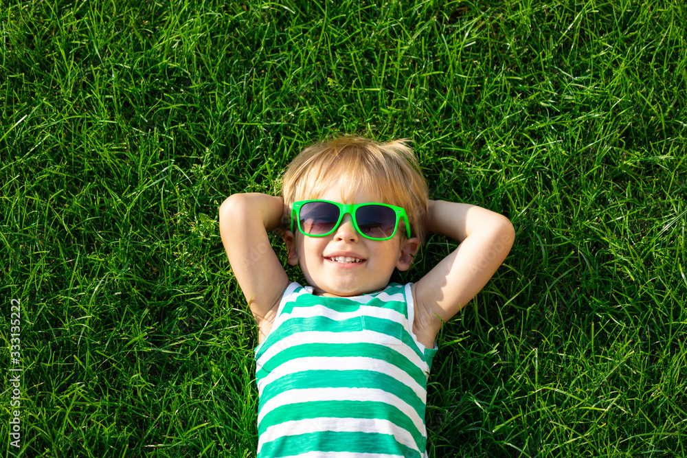 快乐的孩子躺在春天的绿草上