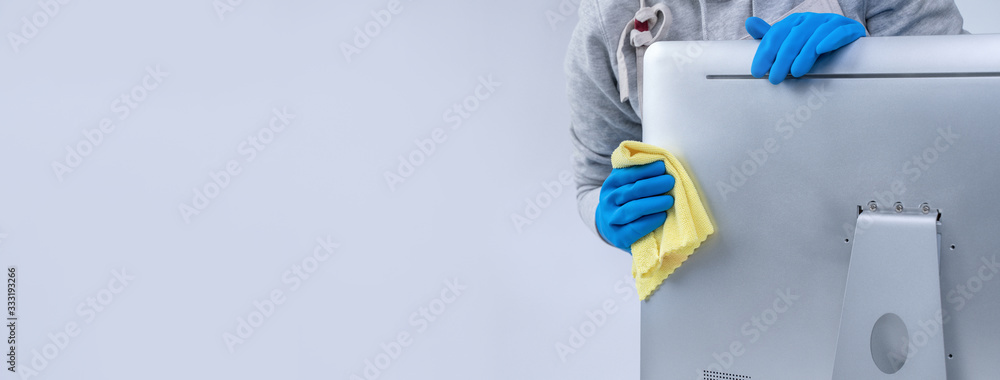 穿着围裙的年轻女管家正在用蓝色手套清洁银色电脑表面，湿漉漉的黄色ra