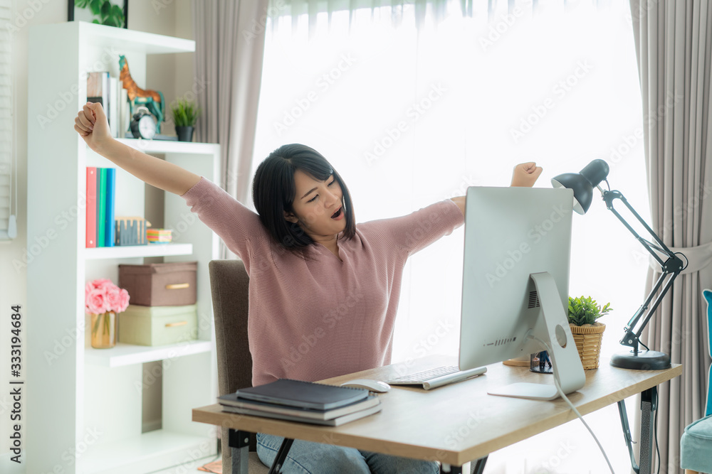 Asian business woman work from home and stretching her body because feel tired and sleepyafter worki