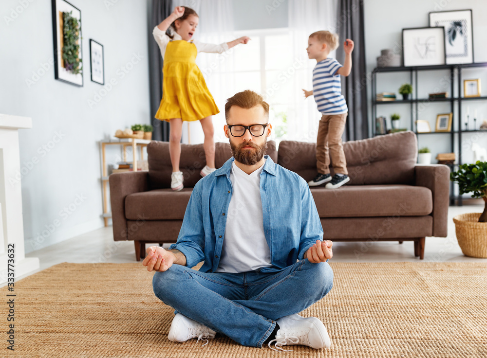 Father meditating in room with playful kids