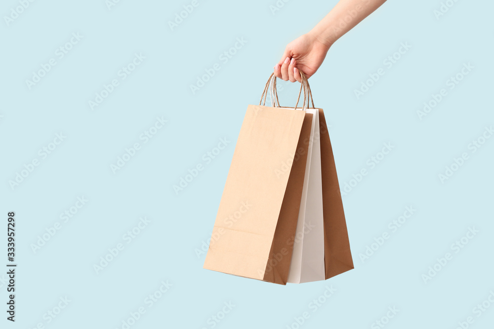 Female hand with paper shopping bags on color background