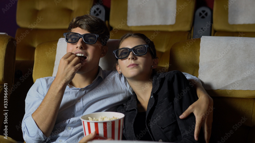 电影院里的男男女女戴着3D眼镜看电影。饶有兴趣地看着屏幕，e