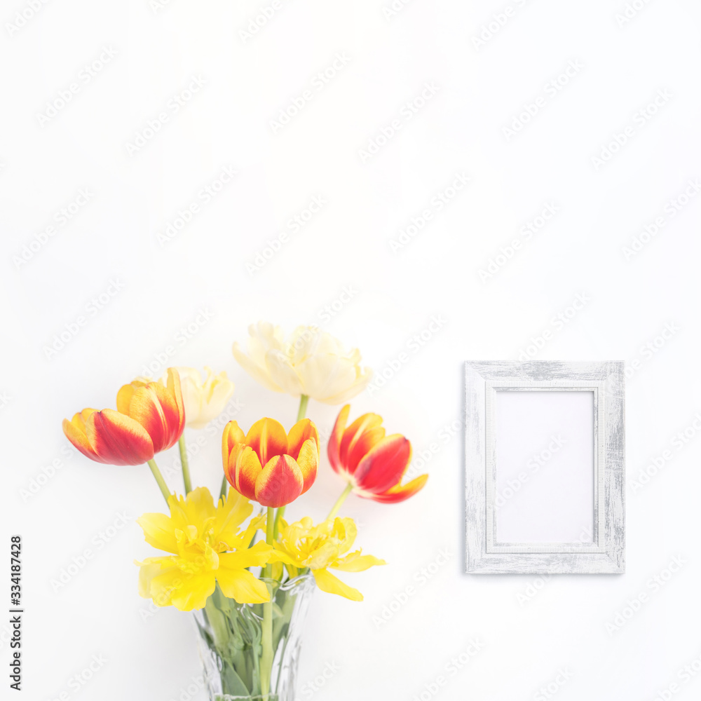 玻璃花瓶里的郁金香花，相框放在白色木桌上，背景是干净的w
