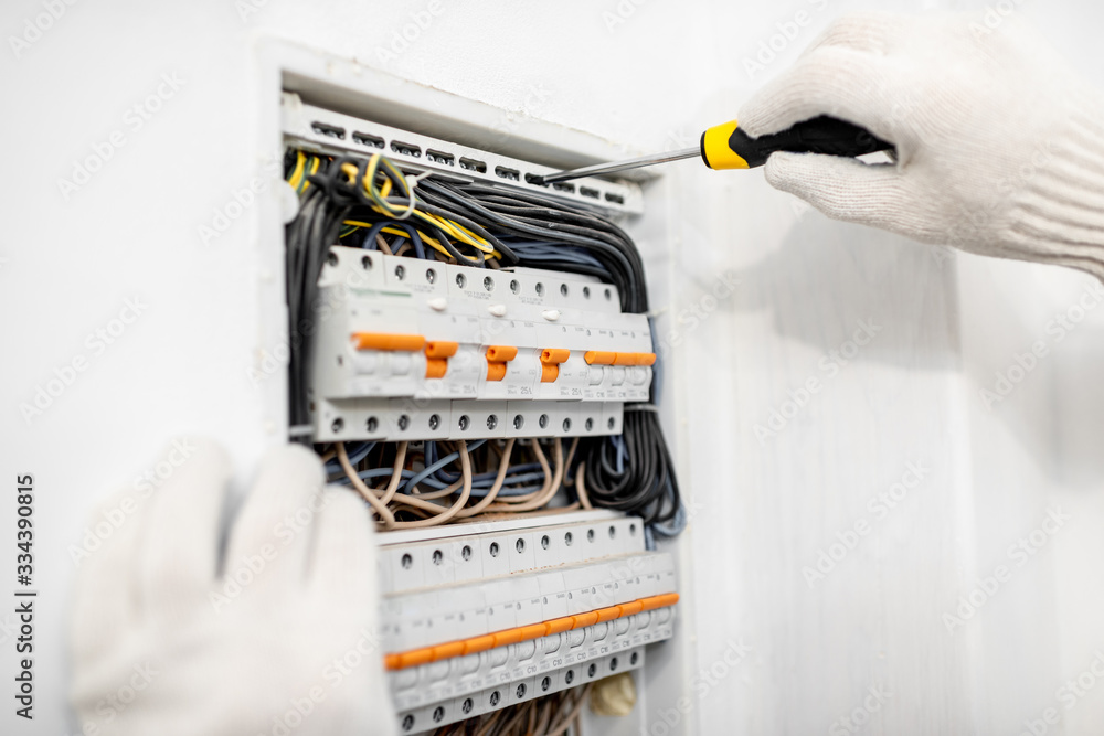Electrician installing or repairing apartment electrical panel, close-up view