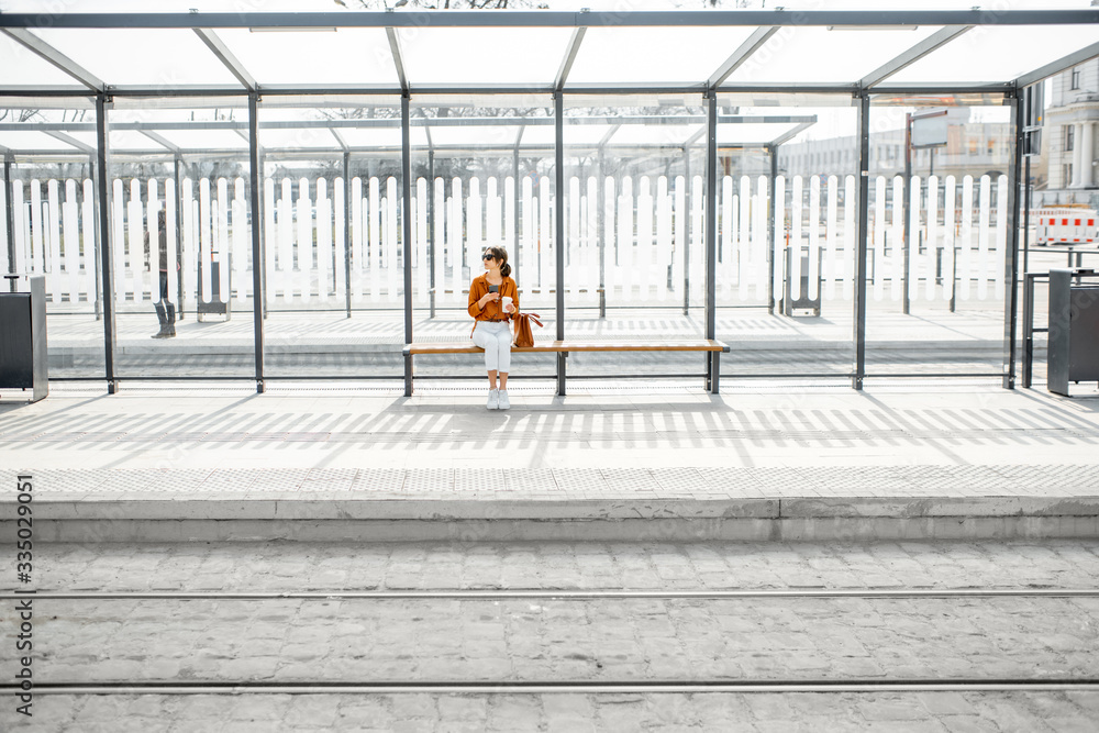 一个阳光明媚的户外，一个女人独自坐在公共交通站，现代人的总体规划
