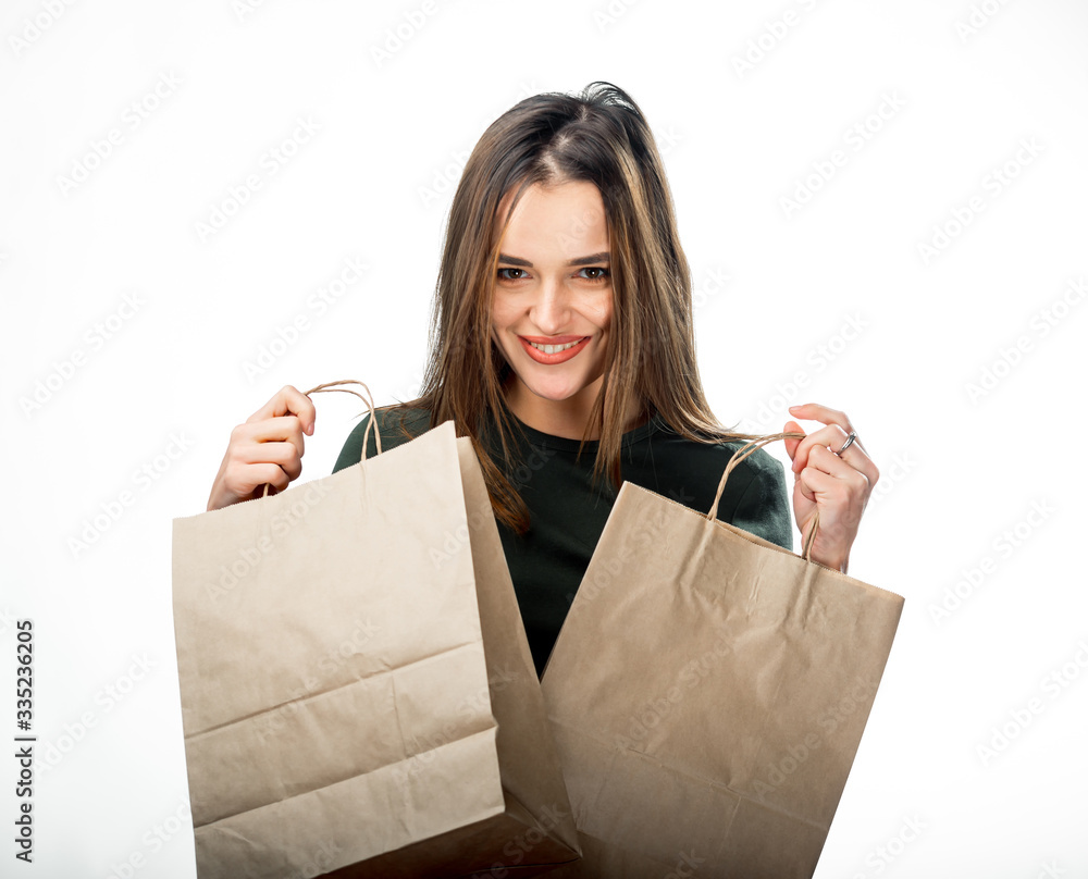 年轻的美女拿着两个白色背景的杂货购物袋。一个女人拿着棕色纸袋。