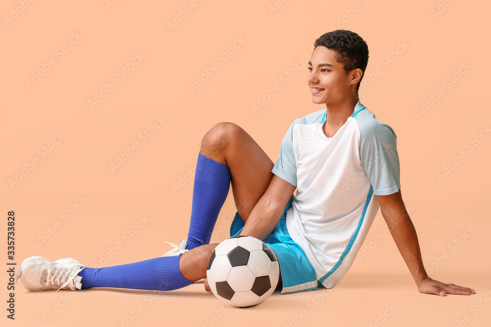 Young African-American football player on color background