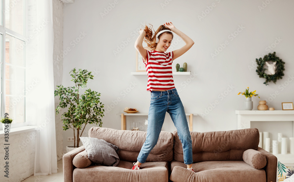 快乐的女人在家里的沙发上听音乐跳舞。