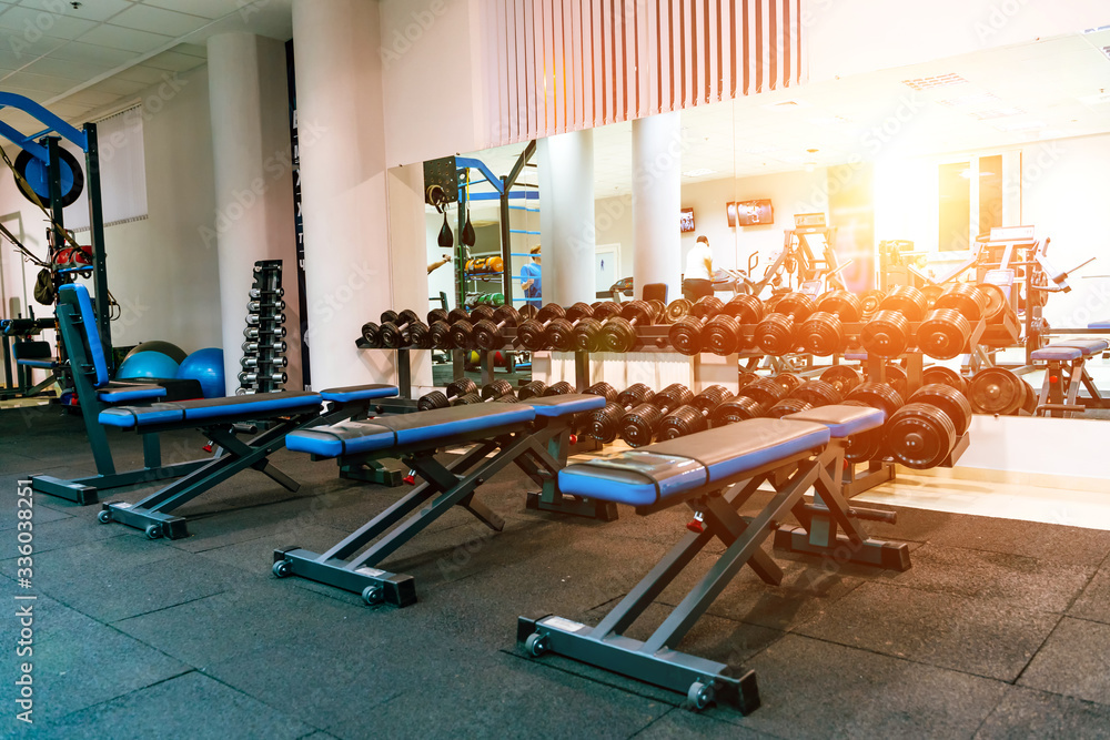 Bench in an exercise room. Equipment and machines at the modern gym room fitness center.