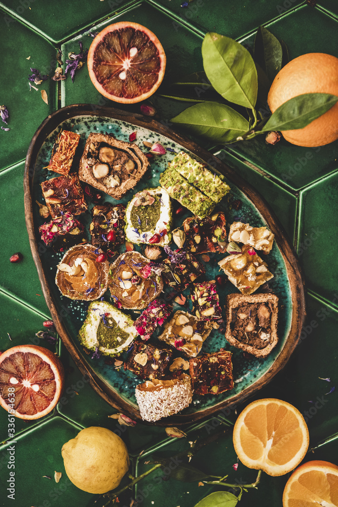 各种土耳其传统lokum甜乐在盘子里平放，新鲜水果在绿色上