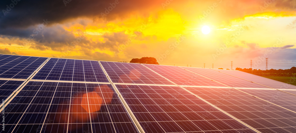 日落天空背景下的光伏太阳能电池板和高压电线，绿色清洁交流发电机