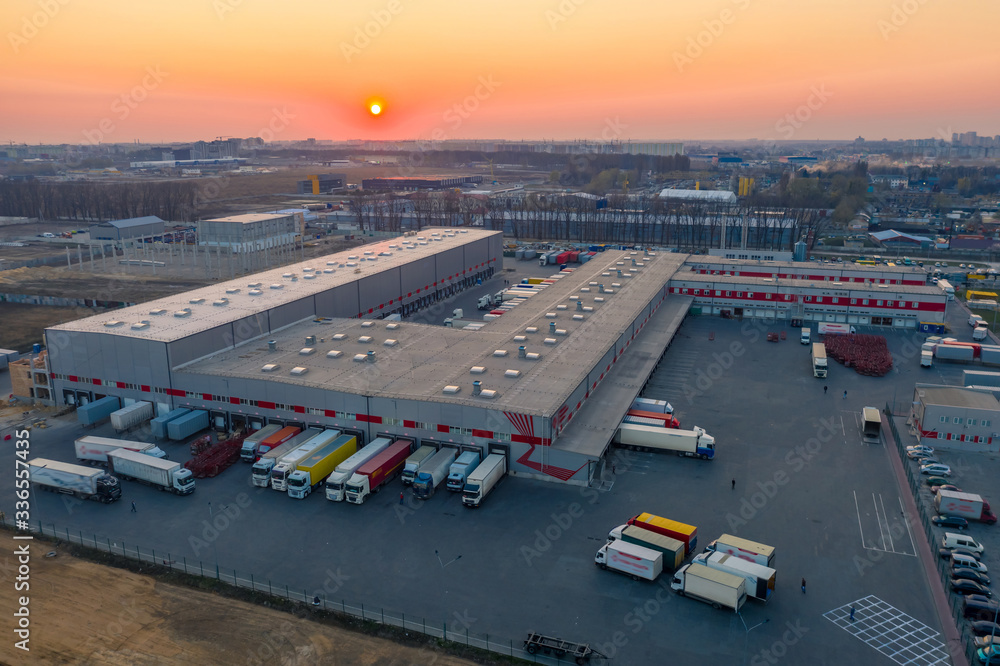 物流园区鸟瞰图，包括仓库、装载中心和许多带货物拖车的半卡车