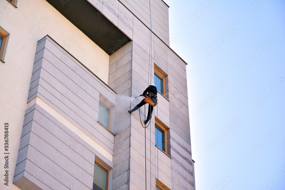 绳索通道立面维护。工人正在清洁公寓楼立面的石头外部。
