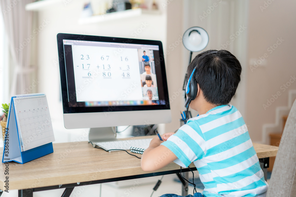 亚洲男生与老师和同学在客厅的电脑上进行视频会议电子学习