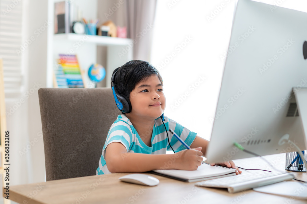 亚洲男生与老师在家客厅的电脑上进行视频会议电子学习。家庭