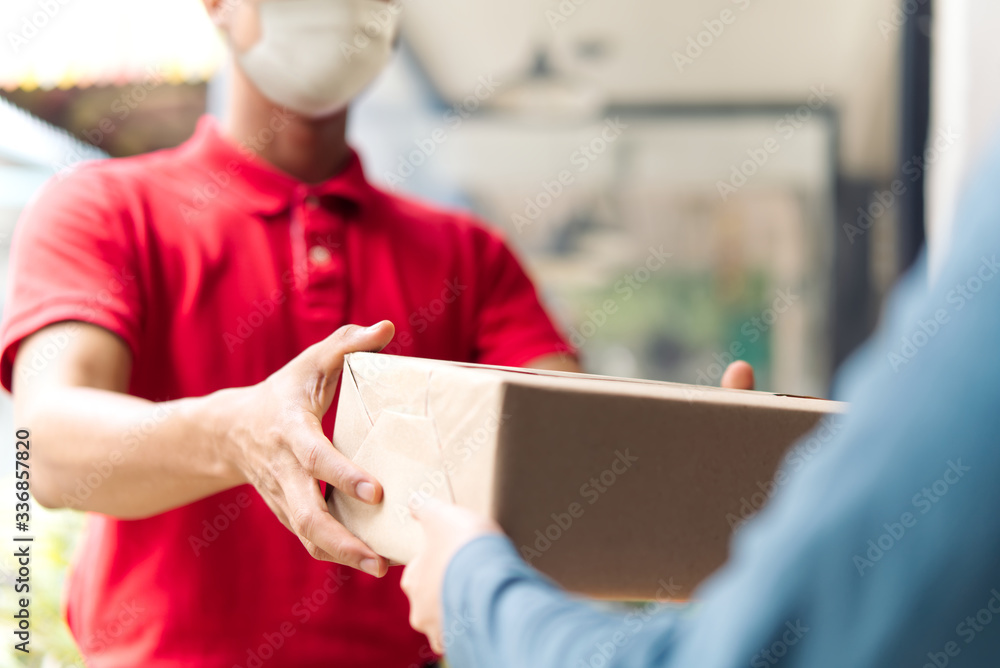 亚洲邮递员，戴口罩的送货员在家门口提着小箱子给顾客送货