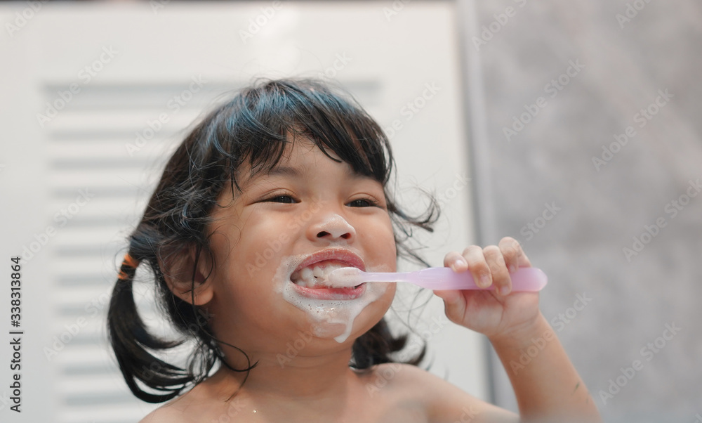牙齿卫生。亚洲可爱的小女孩或孩子在浴室用牙刷刷牙。治愈